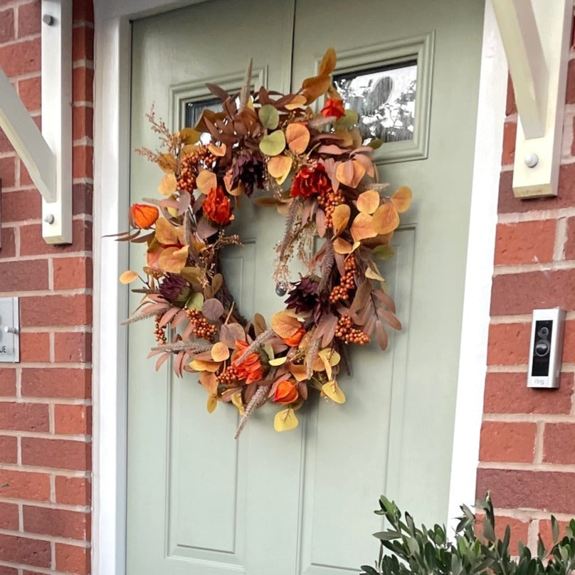 Sacha Autumn Wreath with russet faux foliage, berry sprigs and autumn flowers on a large grapevine base, styled on a front door.