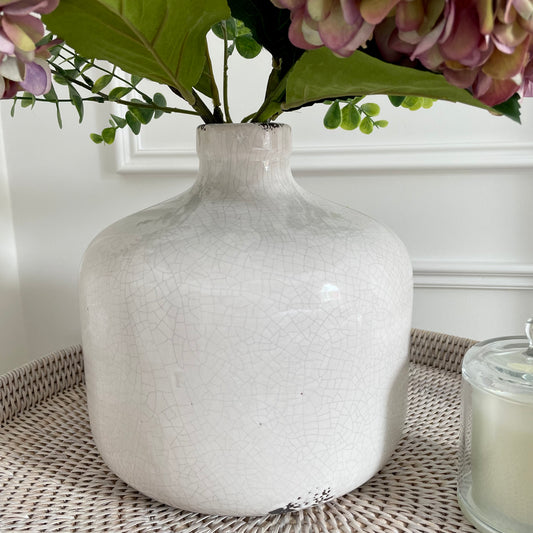 Neutral crackled ceramic Garda Vase with distressed finish, styled with soft greenery on a rustic wooden console table.