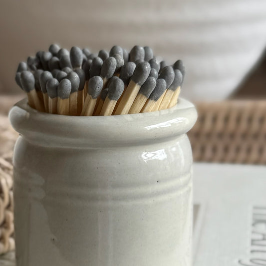 Handmade ceramic match striker crock pot with rustic glaze, styled beside a candle for a cosy, timeless look.