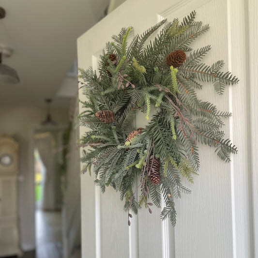 Faux woodland wreath styled on front door for festive decor.