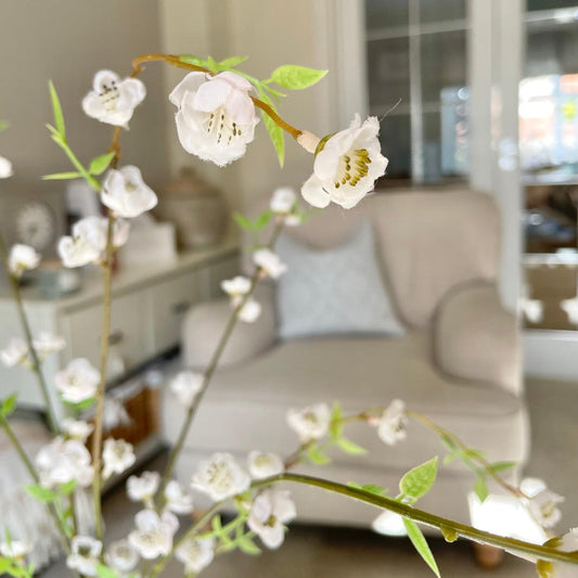 Faux white blossom spray with three stems styled in a rustic stone vase.