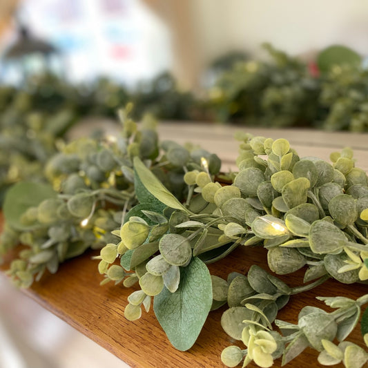 Mixed eucalyptus garland styled along a mantle with fairy lights for a cosy home display.