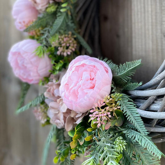Close up of faux peonies, berries and eucalyptus on handmade wreath.