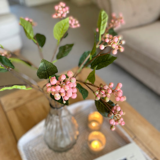 Faux pink berry stem with realistic clustered berries and green foliage, styled in a glass vase.