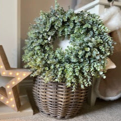 Green flocked eucalyptus wreath in a basket and star decoration.