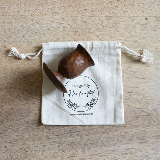 Gift ready forged candle holder with cotton presentation bag. Shown on a wooden table.