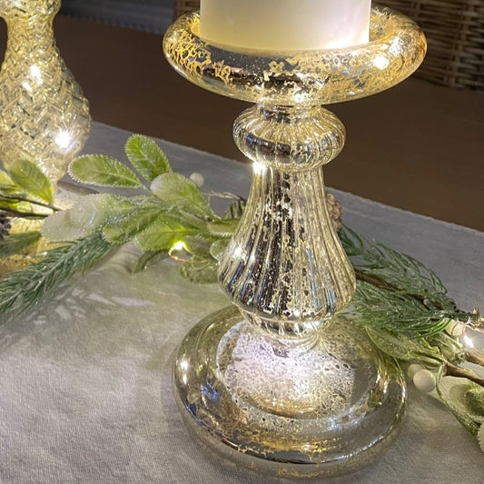 Glass effect LED candlestick holder - 18 cm height styled on a table with garland and table runner. Battery operated.