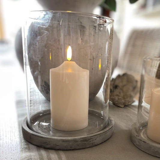 Athena hurricane with natural earthy stone grey base and glass shade styled on a wooden dining table.