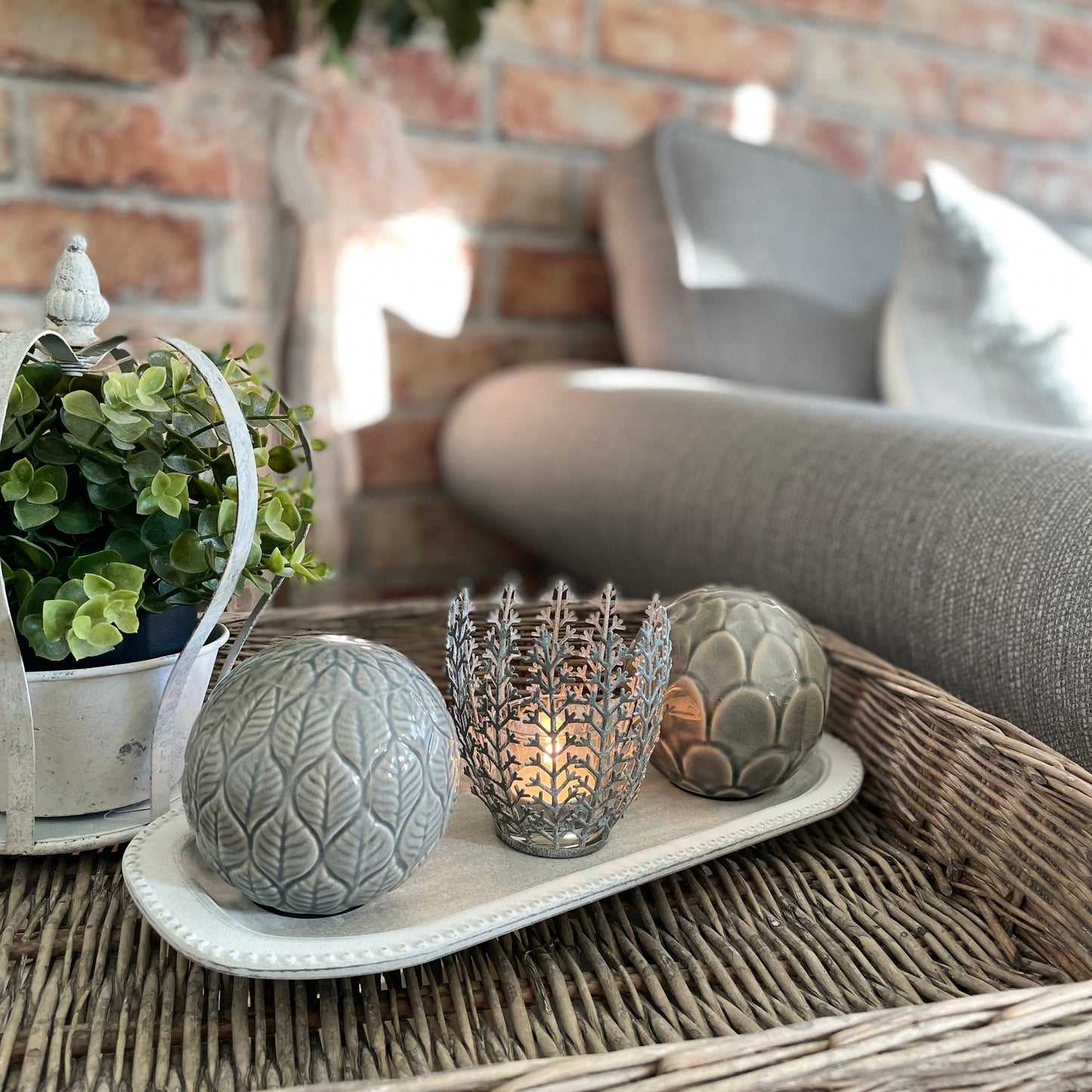 Decorative accessories styled on a wicker table with a brick wall background.