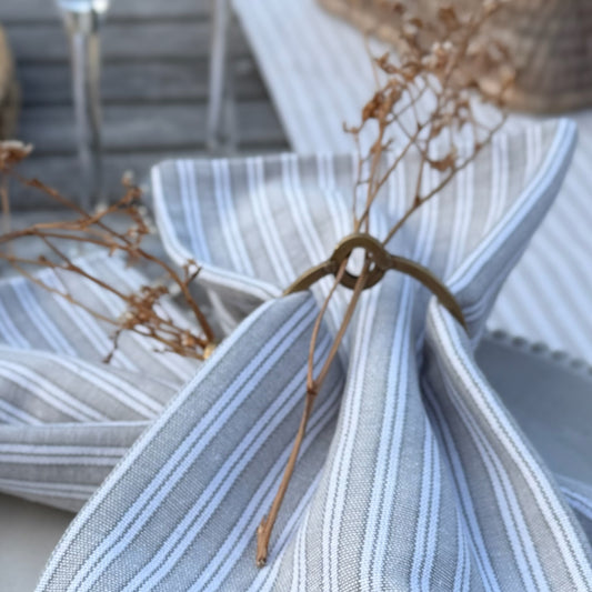 Grey and white striped cotton napkins styled with a matching table runner, perfect for everyday dining or relaxed gatherings.