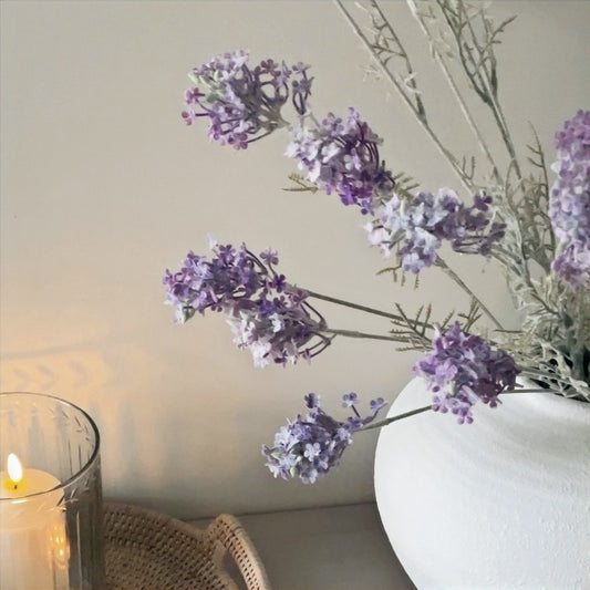 Artificial meadow flower stem adding soft, natural colour and charm to a neutral home setting.