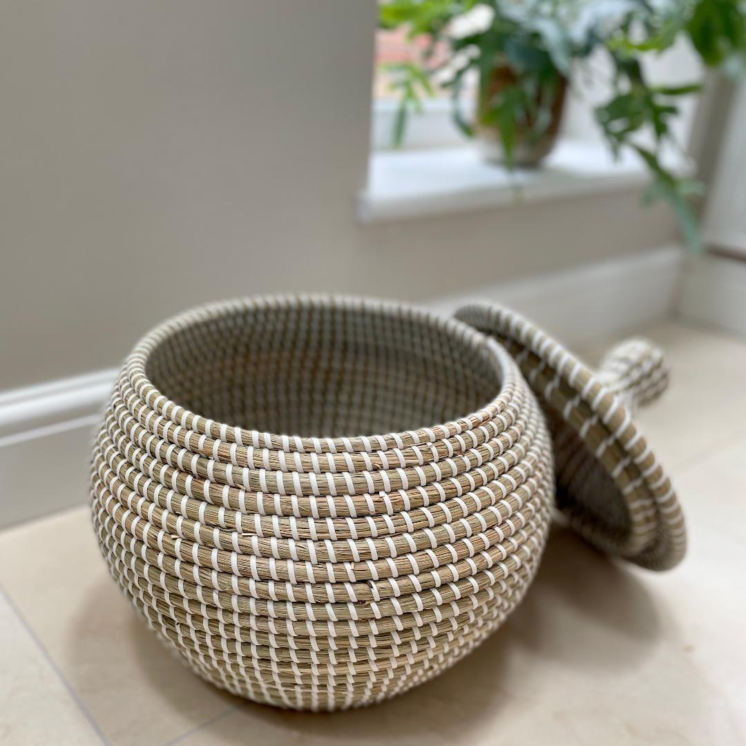 Handwoven natural seagrass basket styled on stone floow with neutral home decor.
