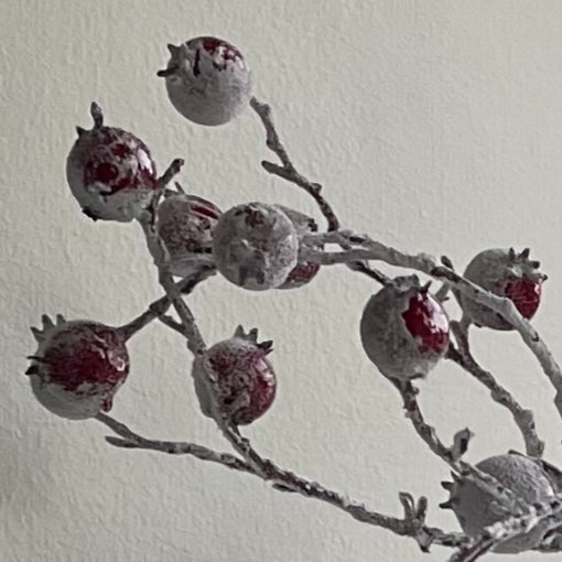 Close up of realistic faux red berries on brown stem. Shown on a white background.