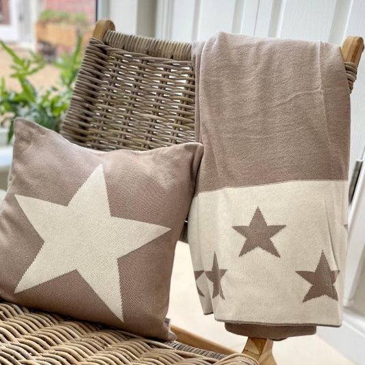 Taupe and ivory reversible star throw, styled on a chair with a cushion.