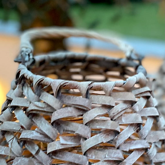 Teardrop shaped rattan lantern with glass insert, styled with a candle to add warm, relaxed lighting.