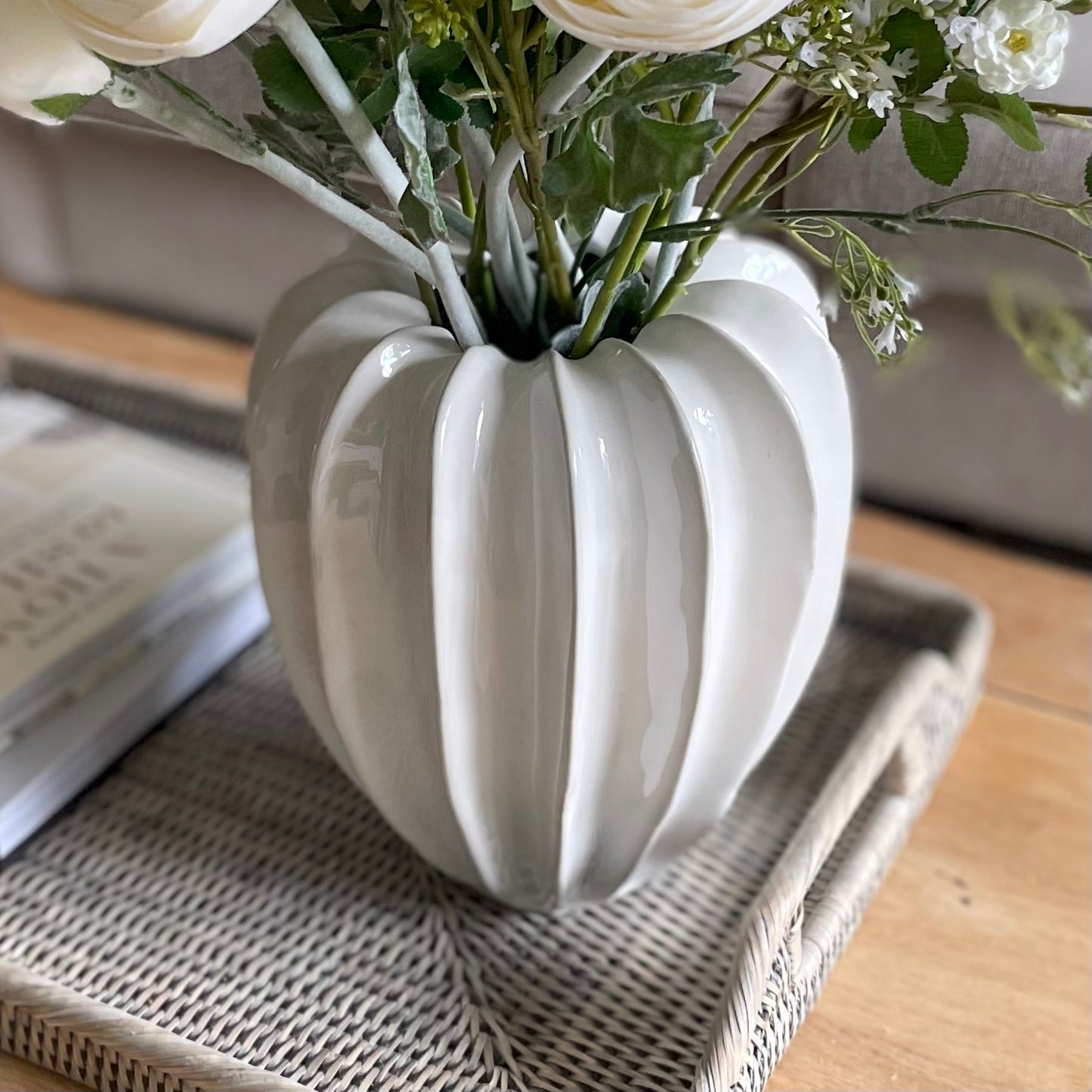 Minimalist contemporary vase in neutral colour. Styled on a rattan tray placed on a wooden coffee table.
