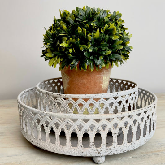 White washed rustic metal trays styled with candles and ornaments on a wooden console, adding vintage charm to a calm, country inspired interior.