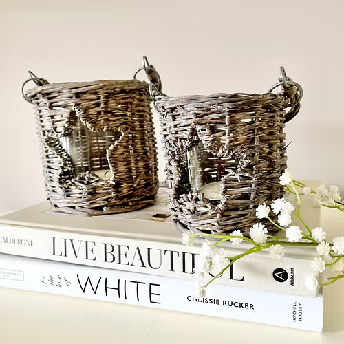 Star shaped cut out wicker candle holders with glass insert, available in two sizes, adding country charm to a room.