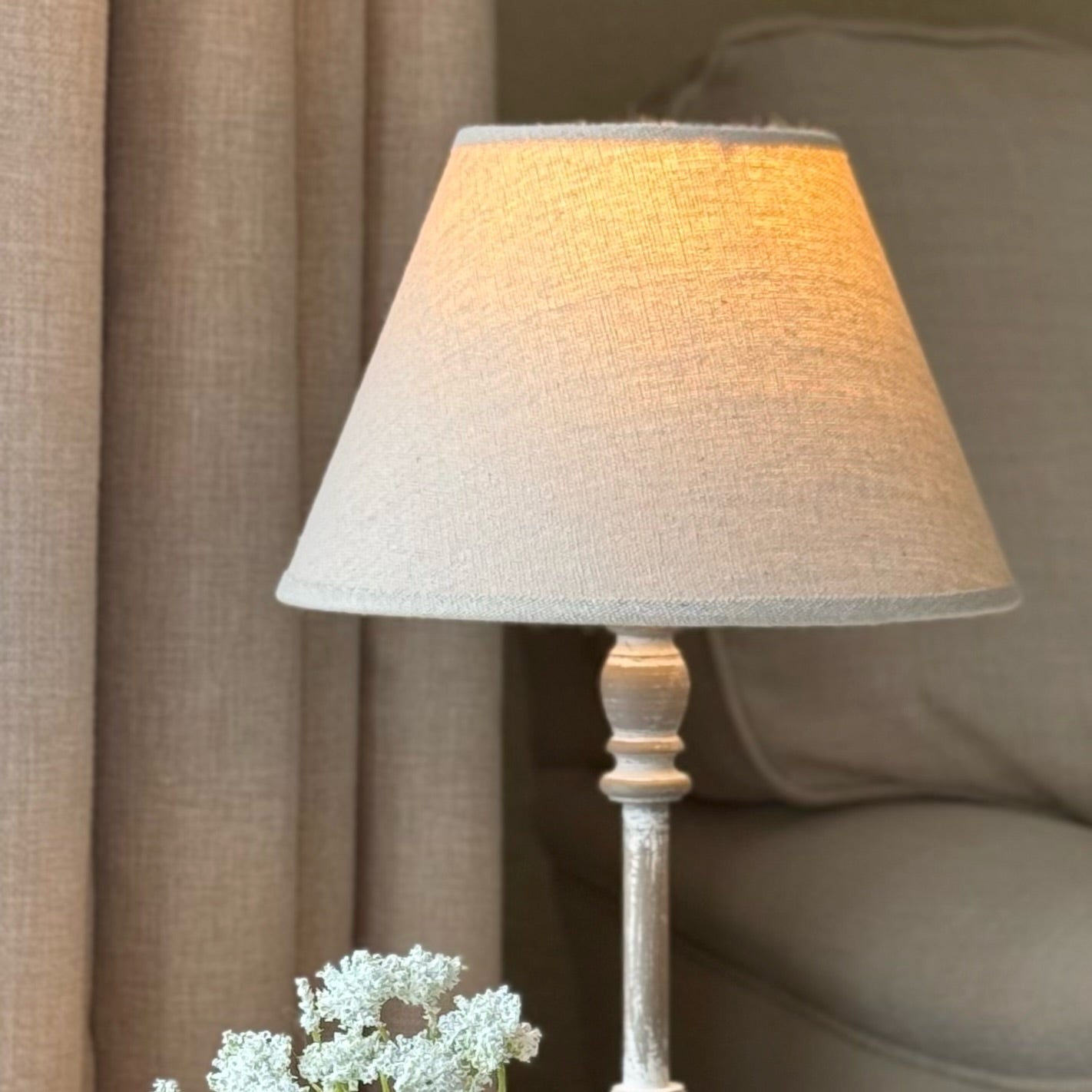 Table lamp with a textured shade on a wooden base in a cosy room setting.