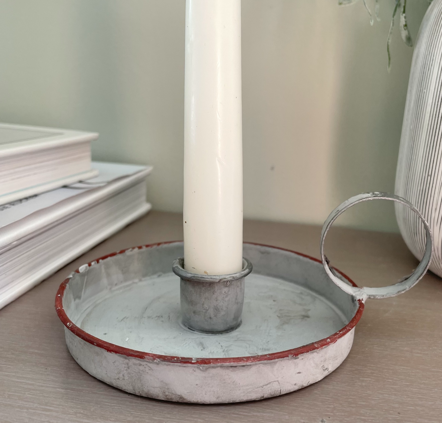 Grey washed wee willie winkie zinc candle holder styled with a taper candle on a console table.