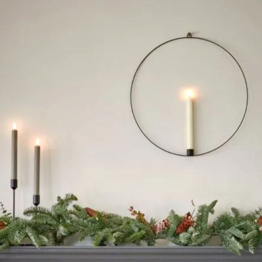 Warm white LED battery operated wax effect candle in a hanging black metal ring with remote control, styled above a fireplace.