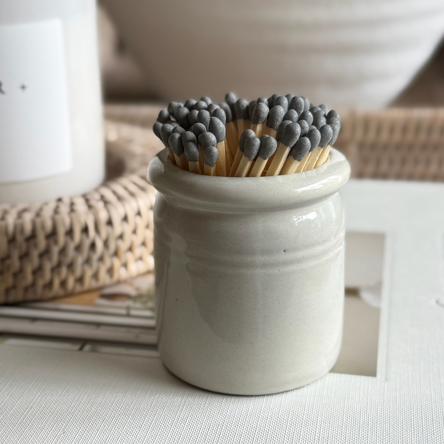 Handmade ceramic match striker crock pot with rustic glaze, styled beside a candle for a cosy, timeless look.