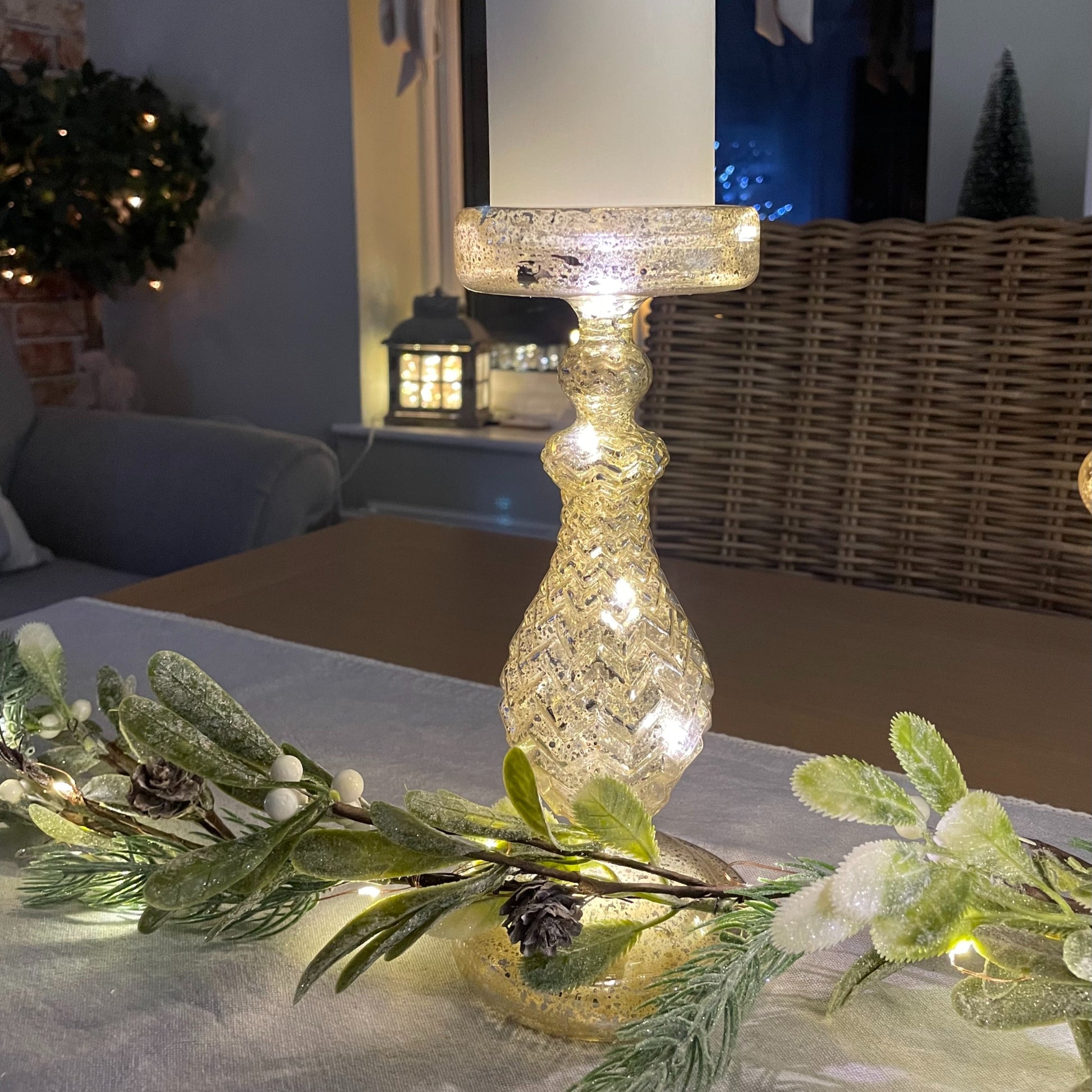 glass effect LED candlestick holder - 24 cm height styled on a table with garland and table runner. Battery operated.
