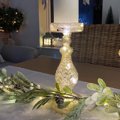glass effect LED candlestick holder - 24 cm height styled on a table with garland and table runner. Battery operated.