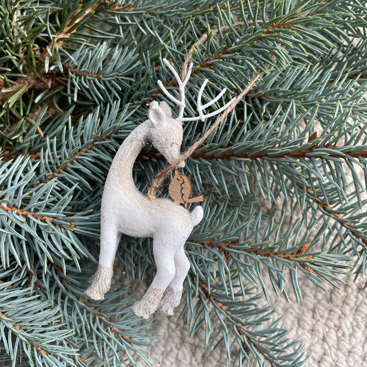 Ivory resin reindeer with subtle sparkle and a small companion bird, styled on a Christmas tree branch.