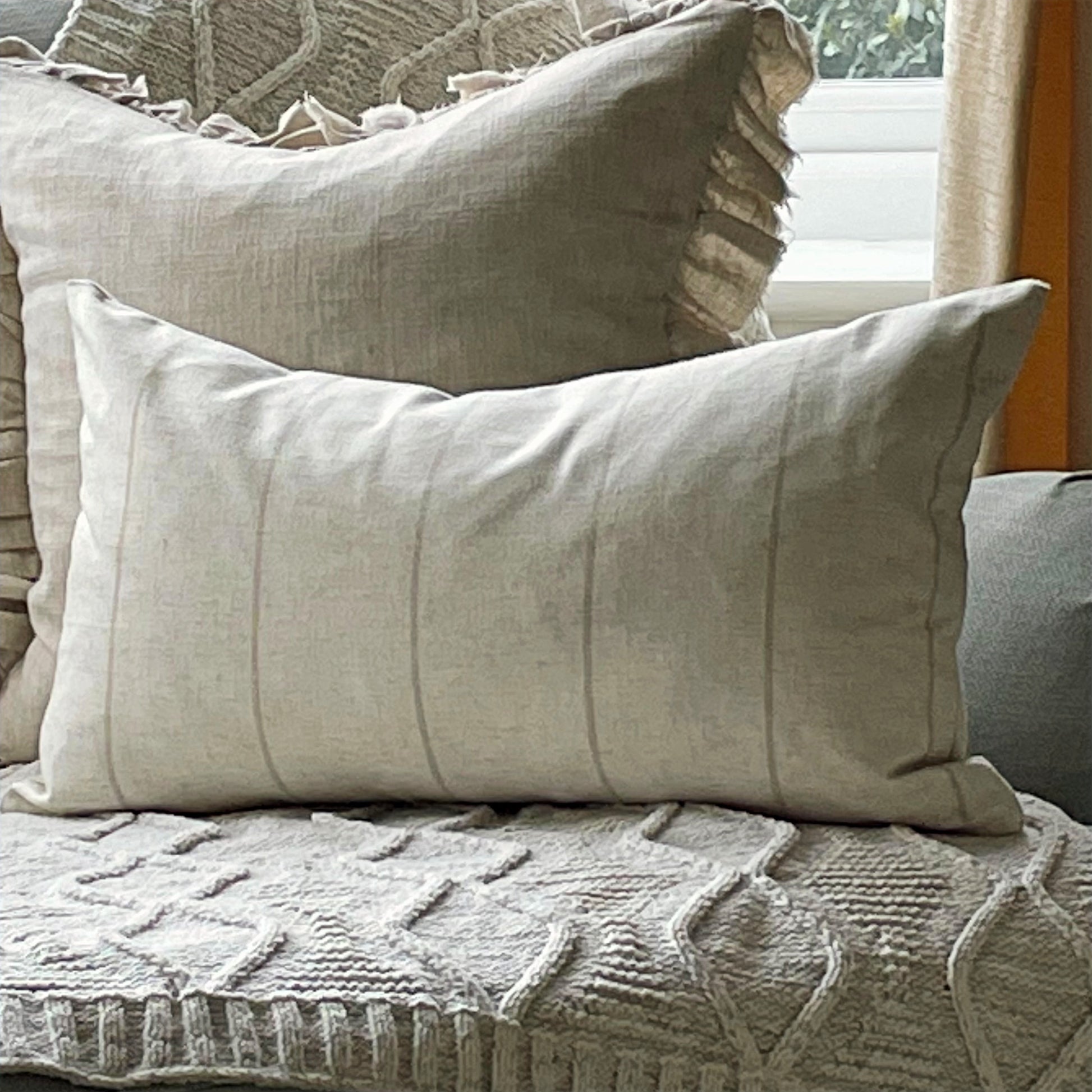 Natural linen blend cushion with thin beige stripes, styled on a neutral sofa for a relaxed country feel.