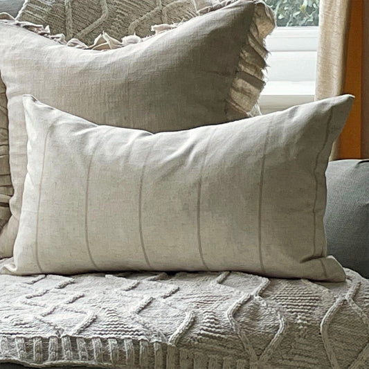 Natural linen blend cushion with thin beige stripes, styled on a neutral sofa for a relaxed country feel.