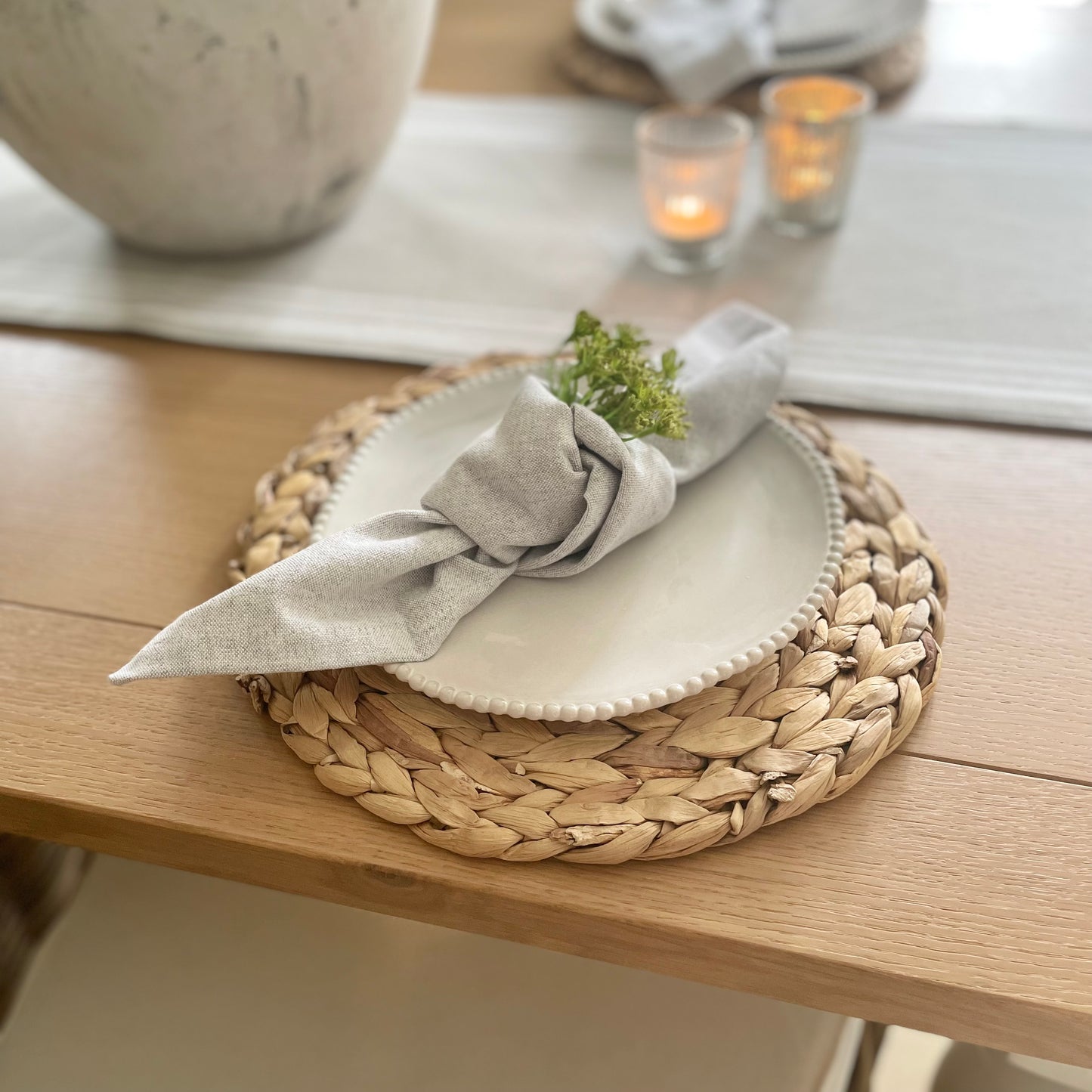White porcelain side plate with organic shape and beaded detailing around the rim, styled on a wooden dining table with grey runner.
