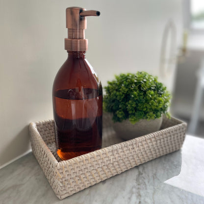 Amber glass refillable bottle with brass effect pump, styled on a bathroom counter.