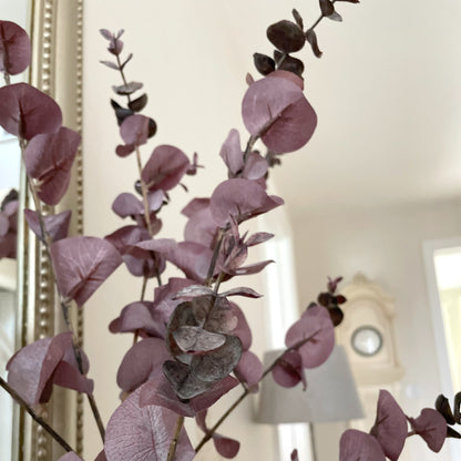 Burgundy faux eucalyptus spray with realistic brown and green tones styled in a hallway.
