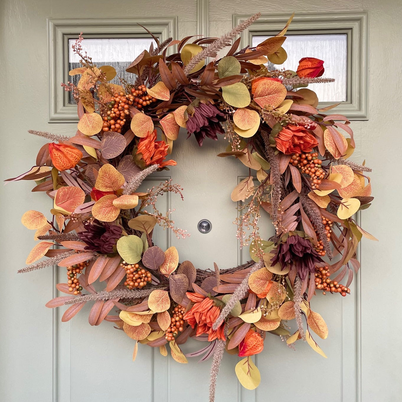 Sacha Autumn Wreath with russet faux foliage, berry sprigs and autumn flowers on a large grapevine base, styled on a front door.