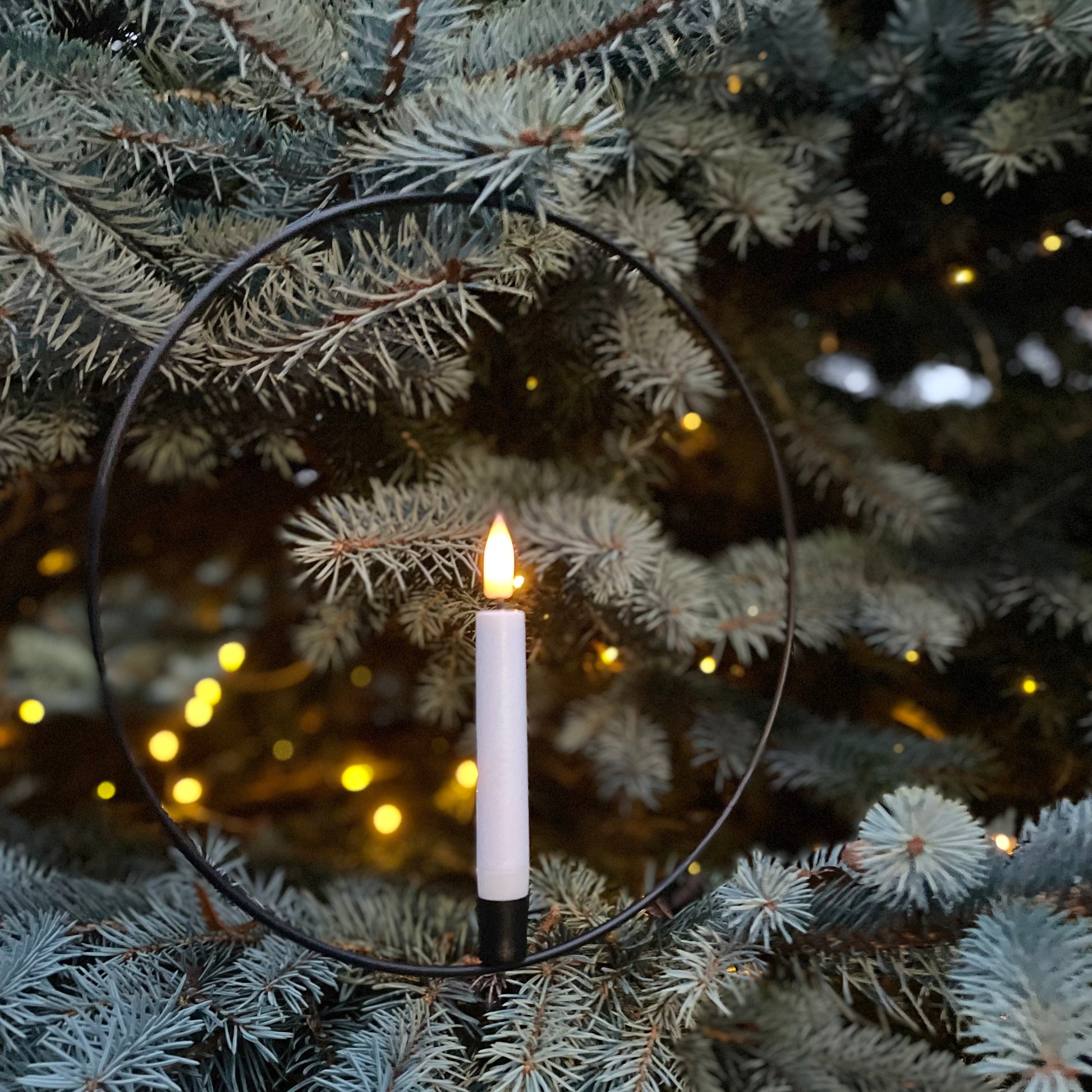 Black metal hanging ring with warm white LED candle and remote control, styled in a cosy interior setting.