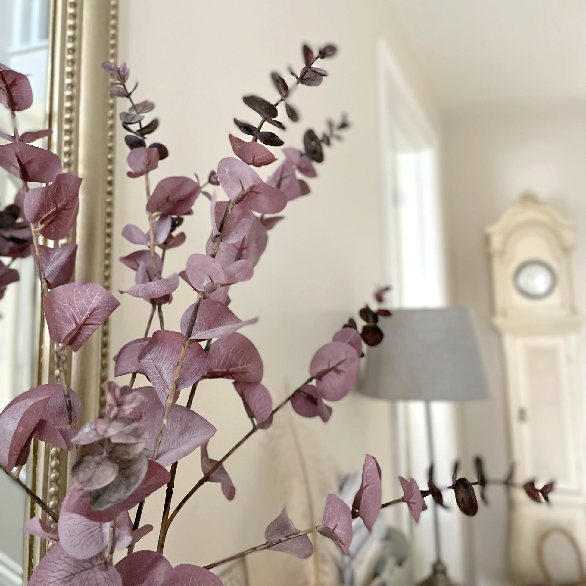 Burgundy faux eucalyptus spray with realistic brown and green tones styled in a hallway.