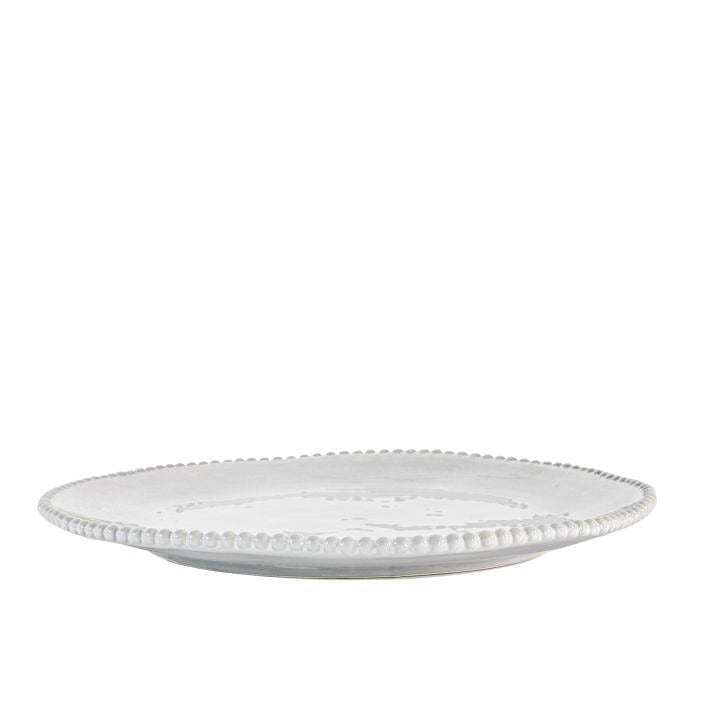 White porcelain dinner plate with organic shape and beaded detailing around the rim, styled in front of a white background.