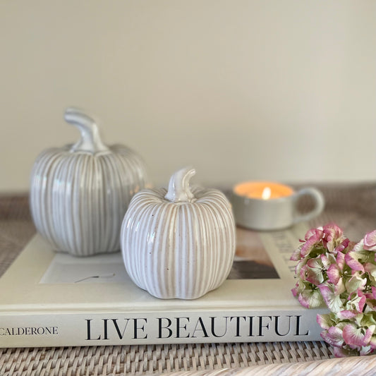 Ceramic glazed pumpkins with ribbed detailing styled on a wooden table for a cosy autumn look.
