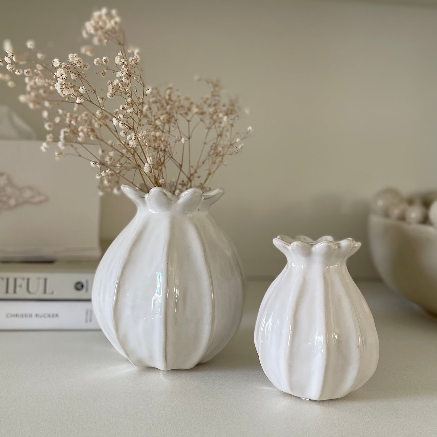 Off white ceramic poppy vase styled alone on a neutral side table.