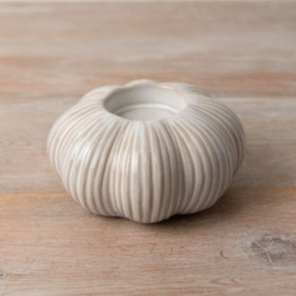 Seasonal ceramic two tone pumpkin tea light holder styled on wooden table.