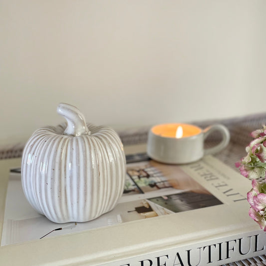 Ceramic glazed pumpkins with ribbed detailing styled on a wooden table for a cosy autumn look.