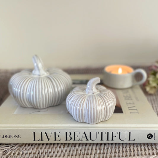 Ceramic squat pumpkins, styled on a book and console table.