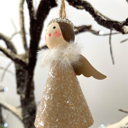 Christmas angel decoration with glitter detail and bells for feet. Hanging on a twinkling snowy branch.