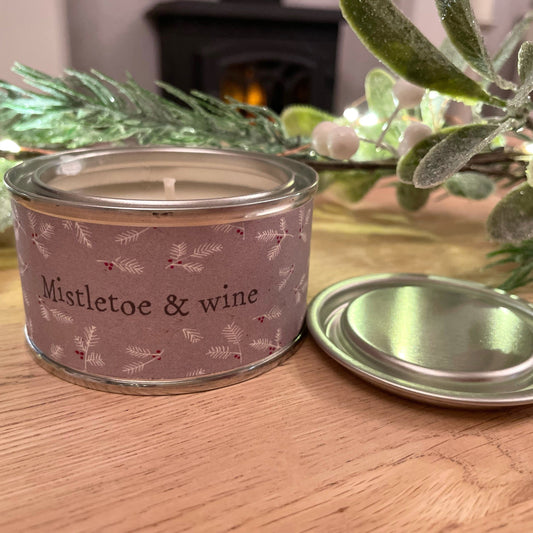Mistletoe and wine christmas scented tin candle, style on a coffee table in a living room.