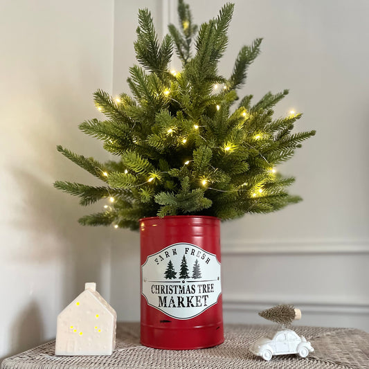 Nostalgic festive home decor using metal Christmas tin. Styled on a rattan base, with a decorative porcelain house and car. 