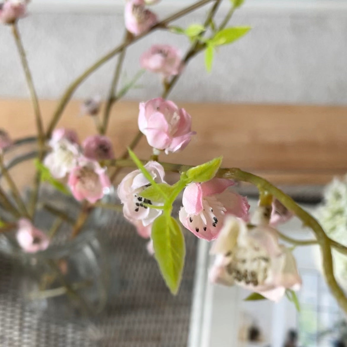 Faux pink blossom spray with three delicate stems styled in a vase.