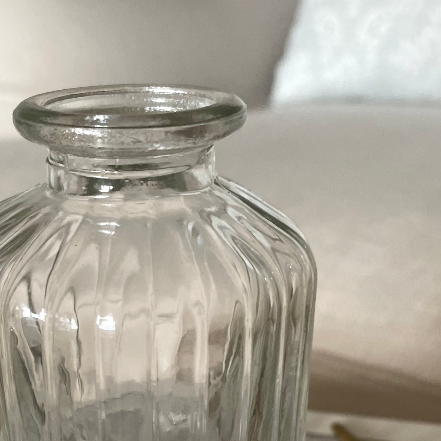 Close up of glass bud vase shown on a neutral background.