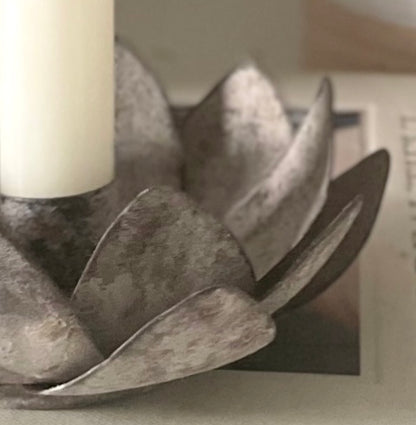 Close up of open lotus flower candle holder styled with Danish candle. Placed on a decorative book.