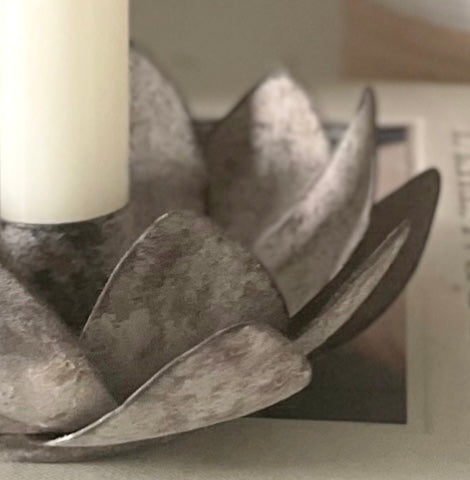 Close up of open lotus flower candle holder styled with Danish candle. Placed on a decorative book.